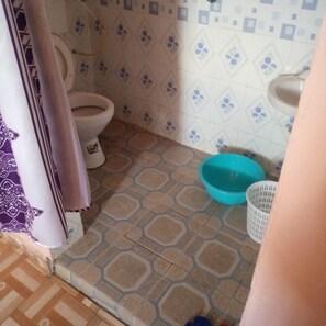 A bathroom with a toilet, a blue basin, and patterned floor tiles. - Duplex Lodge (Nakuru)