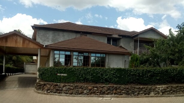 A two-story building with a reception area, paved driveway, and stone wall. - Top Cliff (Nakuru)