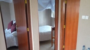 A room with a bed, a chair, and a table with water bottles. - Top Cliff (Nakuru)