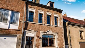 A two-story brick building with a garage door, large windows, and a stone facade. - Holiday Home in Frasnes With Garden (Couvin)