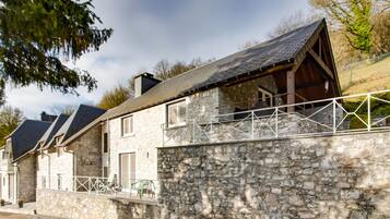 A stone house with a sloped roof and a balcony.