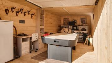 A cozy room with a pool table, wooden walls, and mounted animal heads.