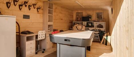 A cozy room with a pool table, wooden walls, and mounted animal heads.