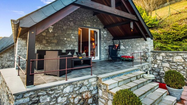A stone house with a covered patio, outdoor seating, and a stone staircase leading to a pool area. - Luxury Pool Villa in Sosoye (Anhée)