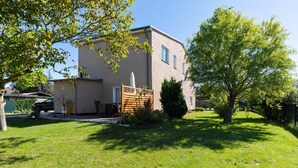 Un immeuble de deux étages doté d’un balcon, d’un petit jardin et d’un arbre.
