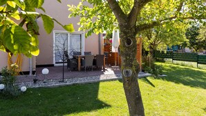 Un espace patio aménagé avec du mobilier d’extérieur, un arbre et un bâtiment en arrière-plan.