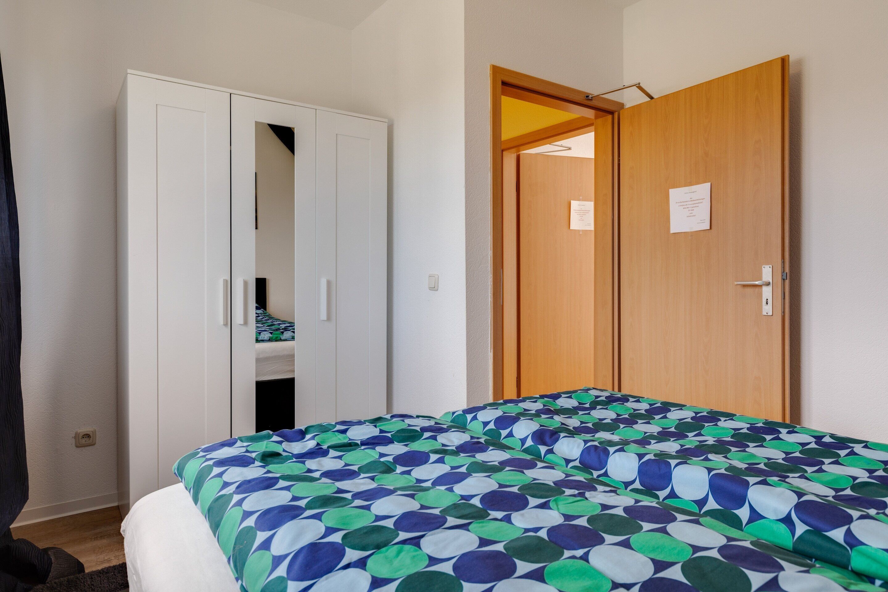 A bedroom with a bed, a wardrobe, and a door.