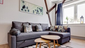 Un salon moderne avec un canapé gris, une table basse ronde en bois et un tapis à motifs.