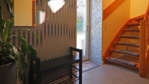 Un escalier avec des marches en bois et une rampe, menant à une porte dotée d’un panneau de verre.