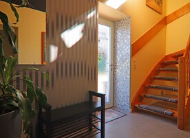 Escada com degraus de madeira e corrimão, levando a uma porta com painel de vidro.