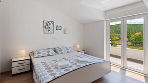 A bedroom with a bed, bedside tables, and a view of greenery through a balcony door. - Bonaventura - Countryside Villa near Split with Private Pool (Muc)