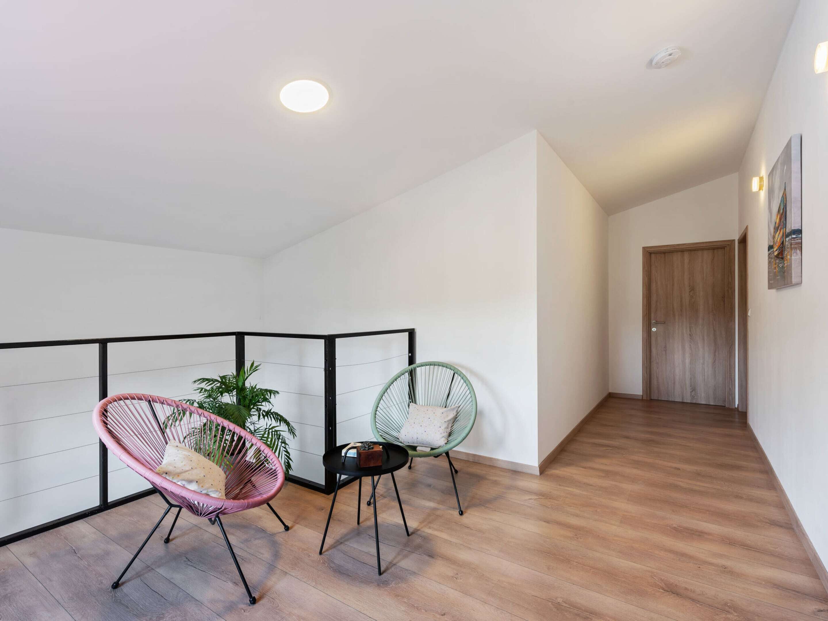 A modern interior with a wooden floor, a black-framed window, and a green chair.
