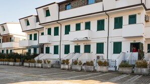 A multi-story building with white walls and green shutters, featuring a central staircase and potted plants. - Belvilla by OYO Apartment in Policastro Bussentino (Santa Marina)