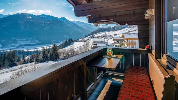Un balcon en bois offrant une vue sur un paysage montagneux enneigé.