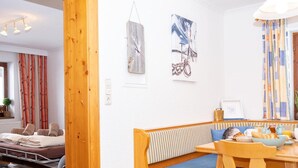 Une pièce chaleureuse avec un banc et une table en bois, un lit agrémenté de serviettes roulées et des œuvres d’art accrochées aux murs.