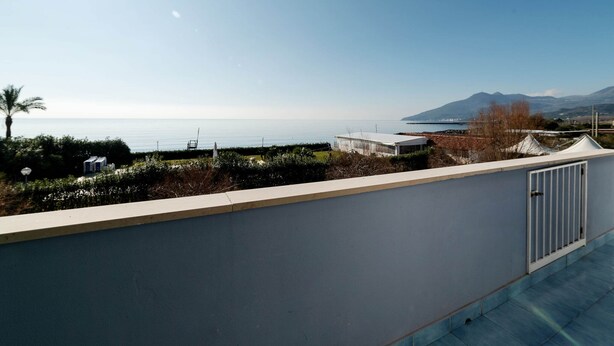 Ein Balkon mit Blick auf das Meer und die Berge.