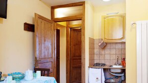 A compact kitchen with a gas stove, sink, and wooden cabinets. A table with a blue tablecloth and various kitchen items is visible. - Sun-kissed Holiday Home With Swimming Pool (Narni)