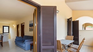 Una sala de estar moderna con un sofá, una mesa de comedor con sillas y un puerta corredera.