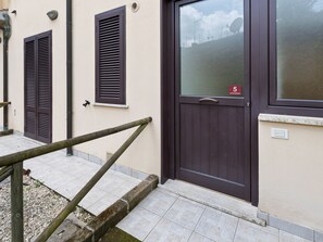 A building with a dark brown door, a window with shutters, and a small sign indicating room number 5. - Belvilla by OYO Trilocale Giglio - Pianoterra (Sorano)