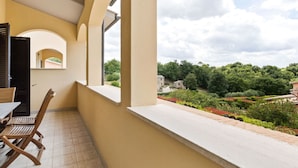 Un balcón con vista a un jardín y edificios.