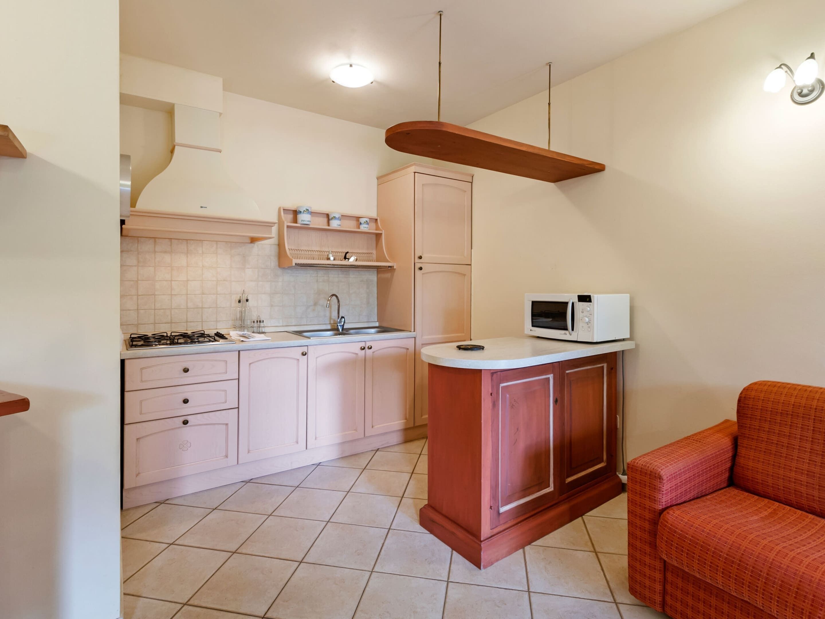 A compact kitchen with a gas stove, a microwave, and a wooden cabinet.