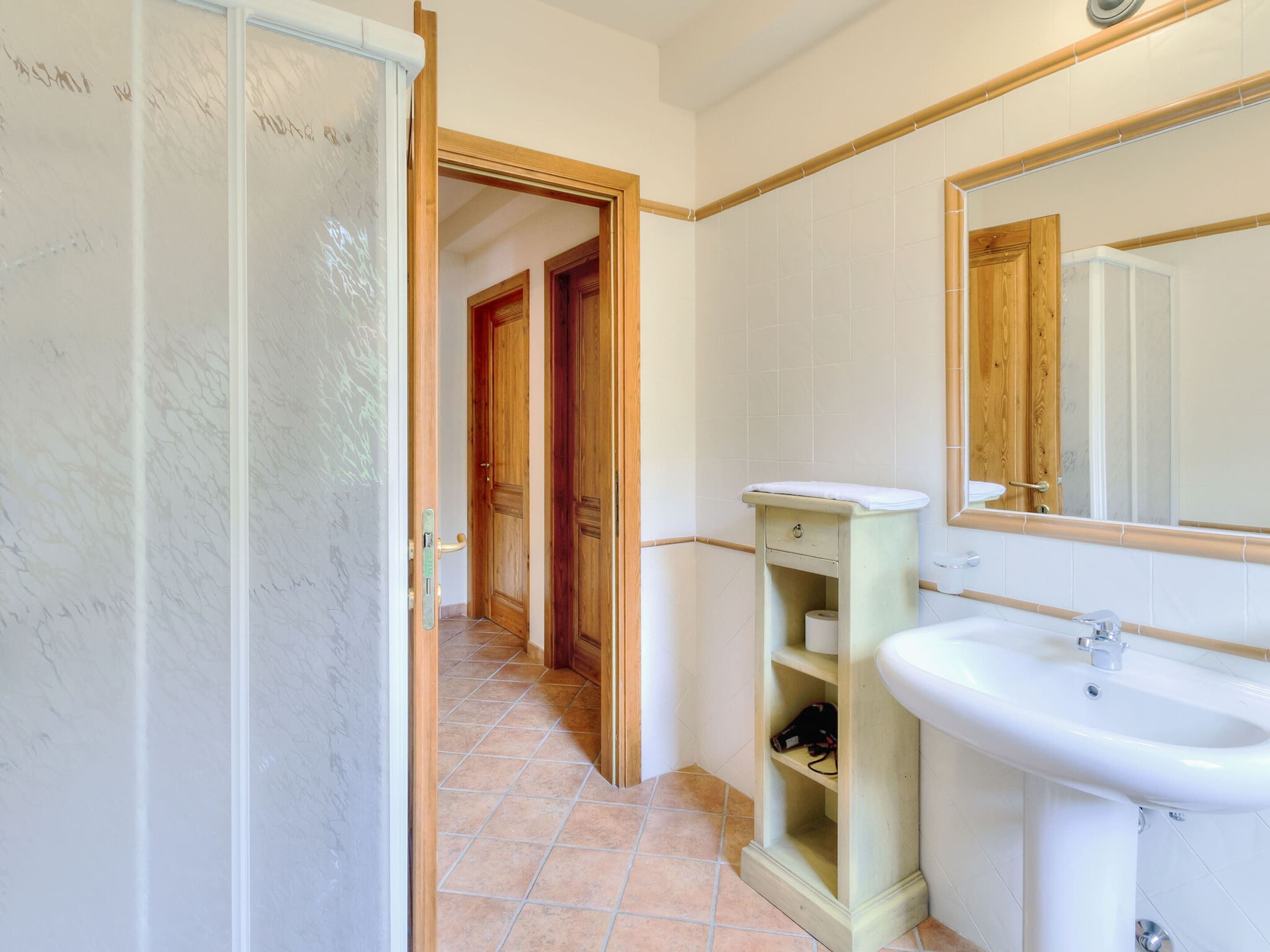 Ein Badezimmer mit Waschbecken, Holzschrank und Spiegel.