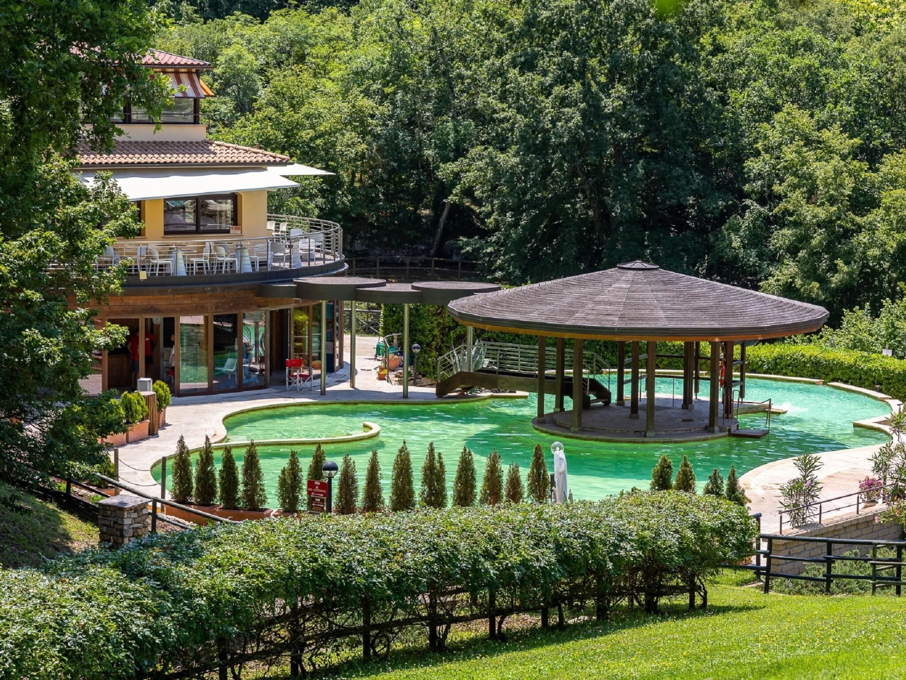 A resort with a swimming pool, a gazebo, and a building with a balcony.