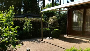 Uma área de pátio com pérgola, plantas em vasos e um caminho de tijolos.