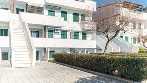A multi-story white building with green shutters, a staircase, and a hedge in front. - Belvilla by OYO Apartment in Policastro Bussentino (Santa Marina)