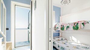 A room with a bunk bed, a door leading to a balcony, and a wall-mounted light fixture. - Belvilla by OYO Apartment in Policastro Bussentino (Santa Marina)