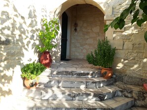 Stunning stone staircase leads to a charming entrance, flanked by lush greenery in terracotta pots.