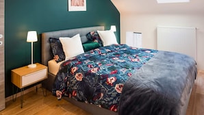 A bedroom with a bed, nightstands, a lamp, a radiator, and a skylight. - Superb Duplex Ideally Located in the Centre of Aywaille (Aywaille)
