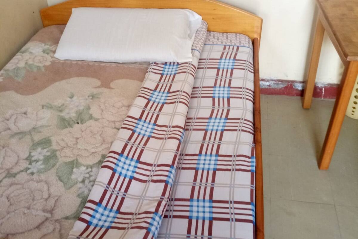 A bed with a floral duvet cover and a plaid blanket.