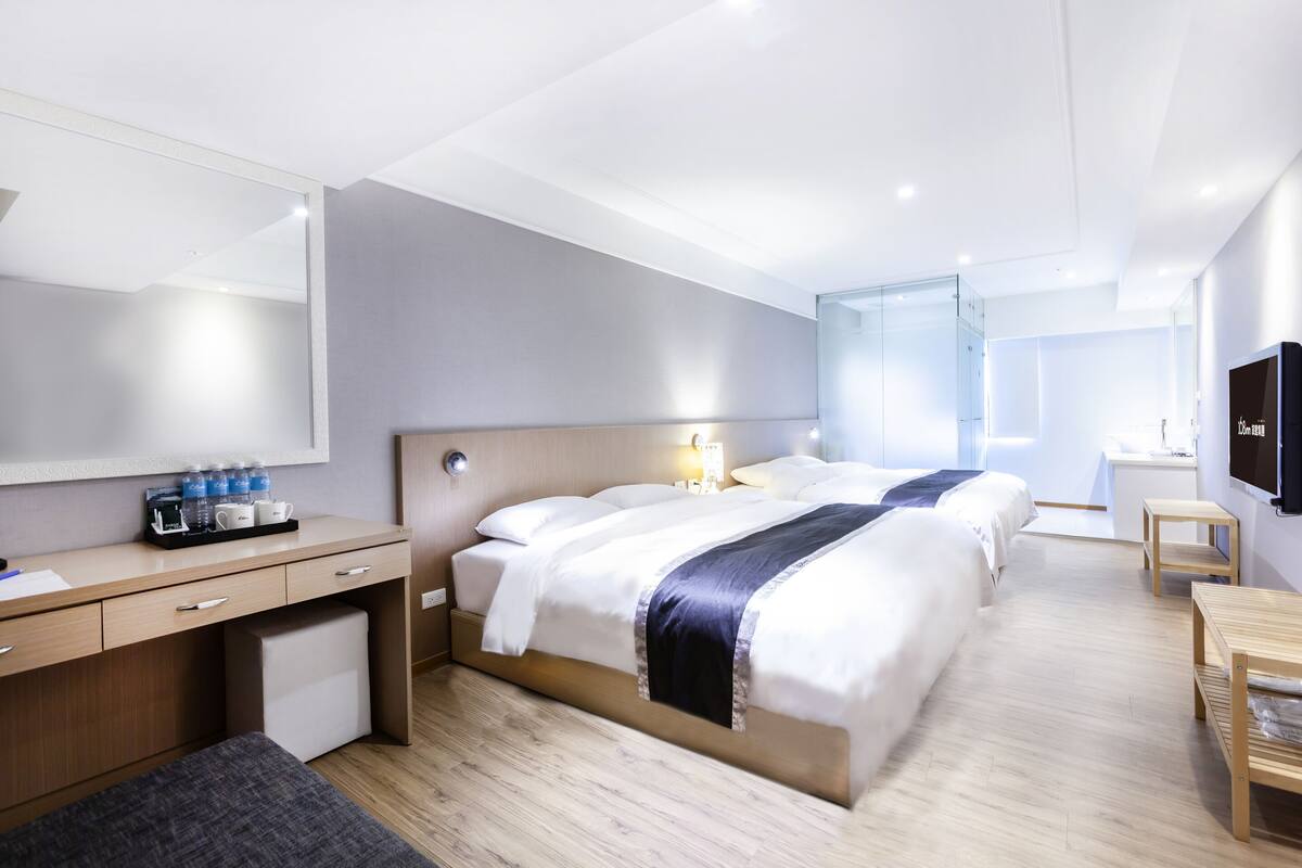 A modern hotel room with a bed, desk, and a TV.