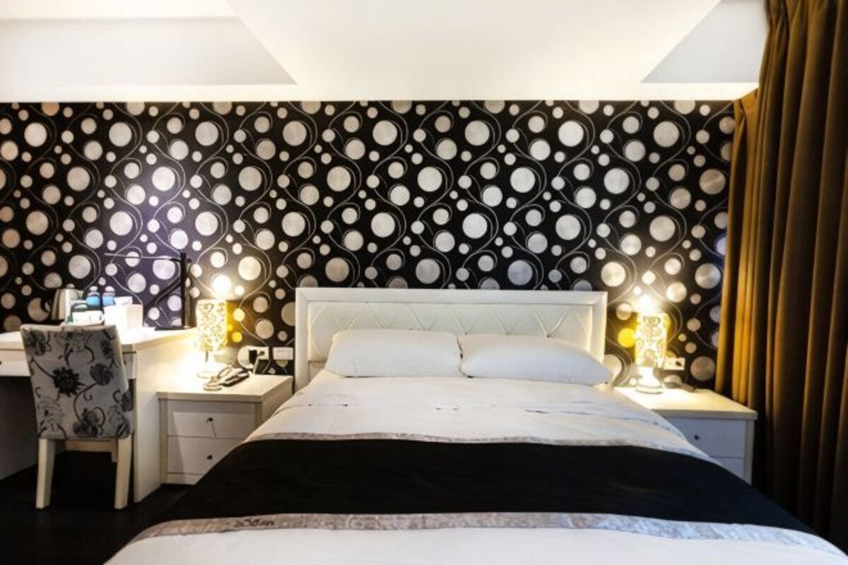 A hotel room with a bed, bedside tables, a desk, and a chair.
