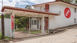 A building with a red and white facade, a gated entrance, and a sign with "OYO" branding. - Hotel Paraje Casa Blanca (San Agustin Etla)