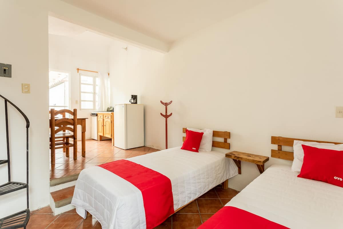 Une chambre d’hôtel avec deux lits, une tête de lit en bois, un bureau et une chaise.