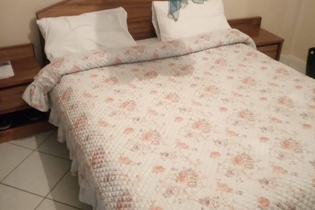 A neatly made bed with a floral-patterned quilt and white pillows.