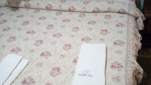 Una cama bien hecha con ropa de cama floral y una toalla blanca.