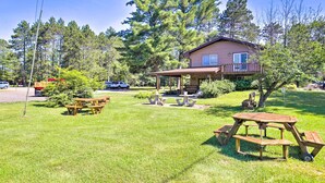A house with a covered patio, picnic tables, and a lawn. - Simple Cranberry & Wine Farm Home w/ Fire Pit! (Eagle River)