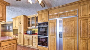 A kitchen with wooden cabinets, a stainless steel refrigerator, and a tiled floor. - Simple Cranberry & Wine Farm Home w/ Fire Pit! (Eagle River)