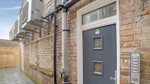 A brick building with a grey door, a metal mailbox, and a wooden gate. - Modern Studio in London Near Wimbledon Park (London)