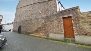 A brick building with a large wooden door and a small window. - Modern Studio in London Near Wimbledon Park (London)