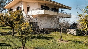A two-story house with a balcony, surrounded by trees and grass. - Holiday Villa With sea View in Paralia Avlidas (Chalcis)