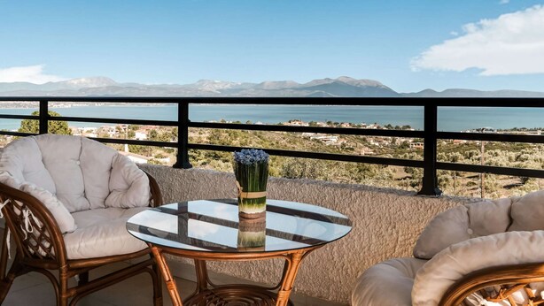 A balcony with wicker chairs, a glass table, and a vase of flowers. - Holiday Villa With sea View in Paralia Avlidas (Chalcis)