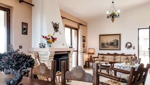 A dining area with a wooden table, chairs, a fireplace, and a chandelier. - Holiday Villa With sea View in Paralia Avlidas (Chalcis)