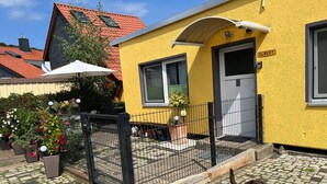 A yellow building with a black gate, a dog, and a potted plant. - Bungalow in Wernigerode (Wernigerode)