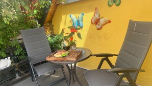 A patio with two chairs, a table, and a yellow wall with butterfly decorations. - Bungalow in Wernigerode (Wernigerode)