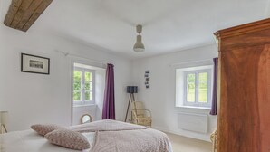 A bedroom with a bed, two windows, a chair, and a wooden cabinet. - Cozy Normandy Escape (Formigny La Bataille)