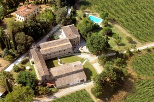 Vista aérea de un edificio grande con varias habitaciones, rodeado de abundante vegetación y una piscina.
